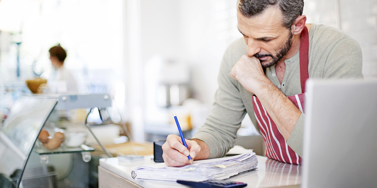 cafe owner focusing on business paperwork behind service counter cafe owner focusing on business paperwork behind service counter