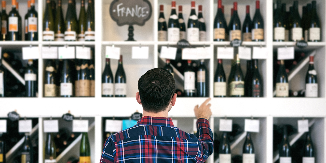 view of back of shopper looking at a wine display labeled "France" view of back of shopper looking at a wine display labeled "France"